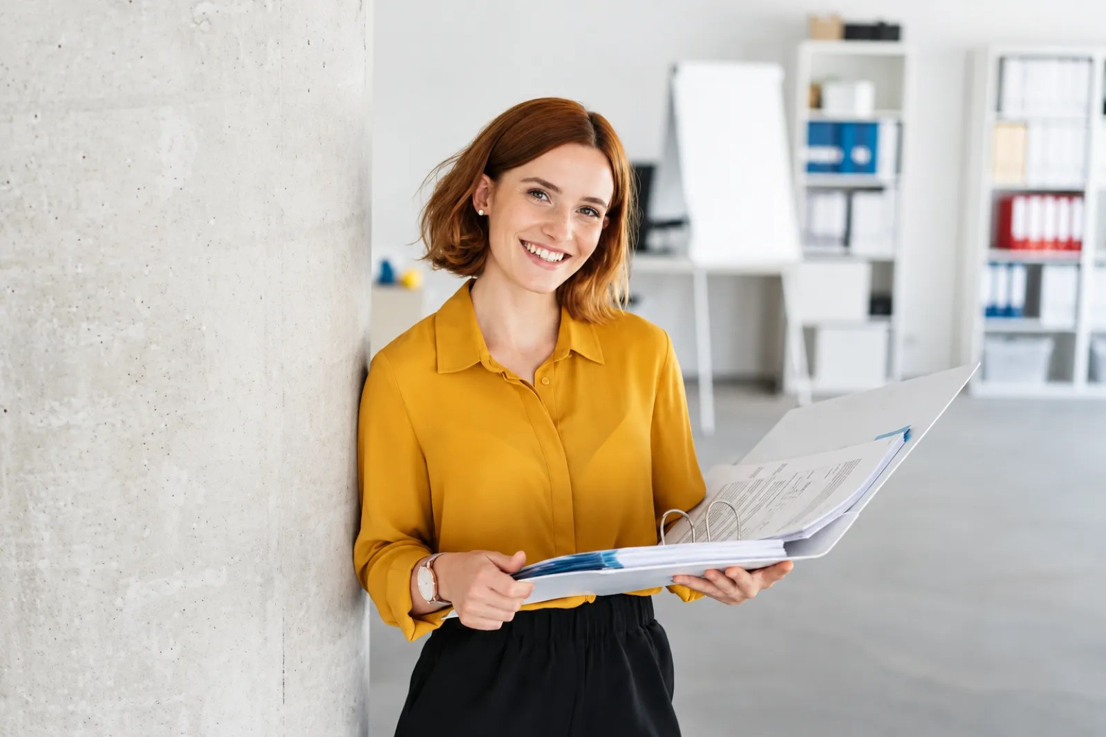 Smiling office manager holding a folder of workplace documents
