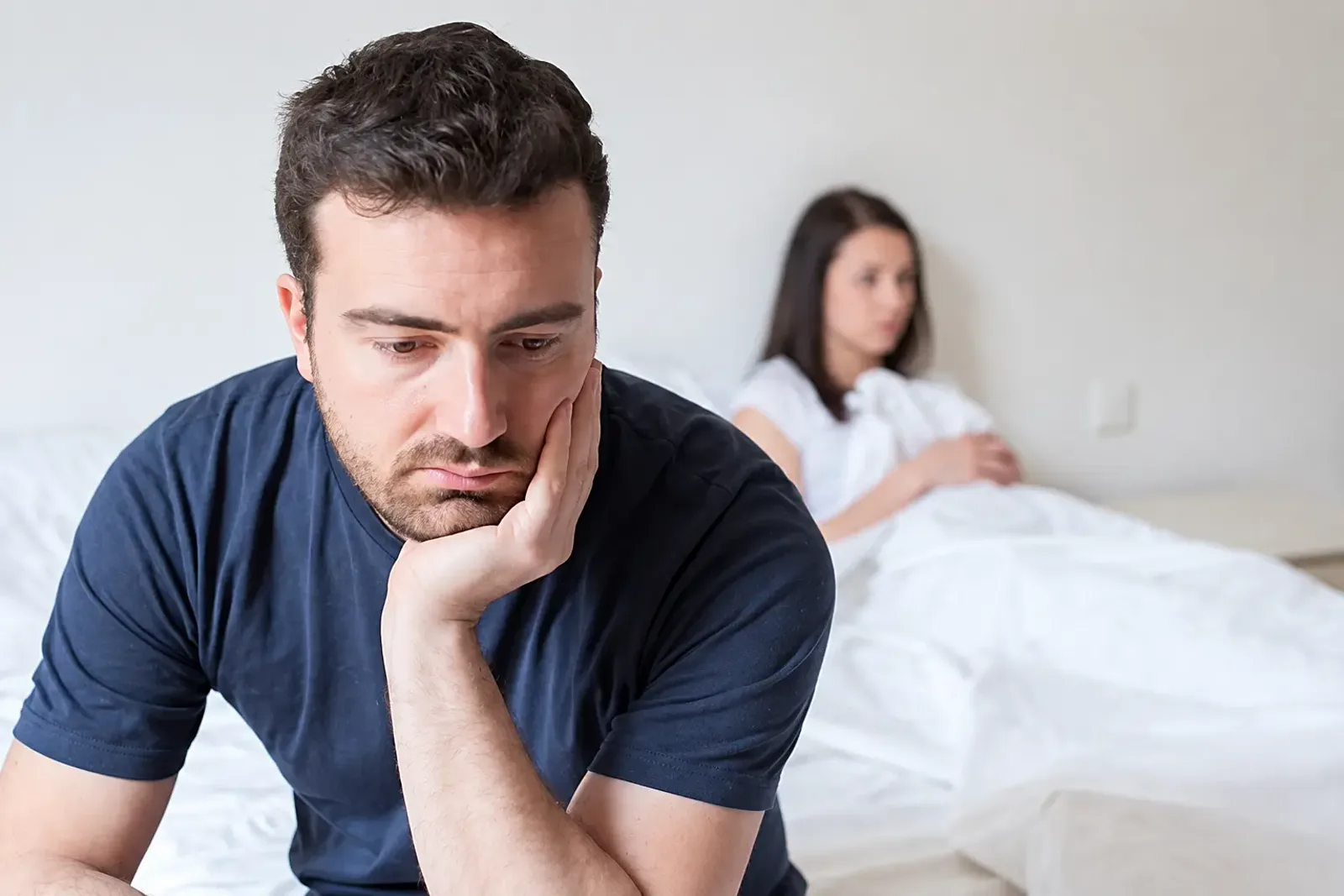 Man sitting thoughtfully on the edge of a bed