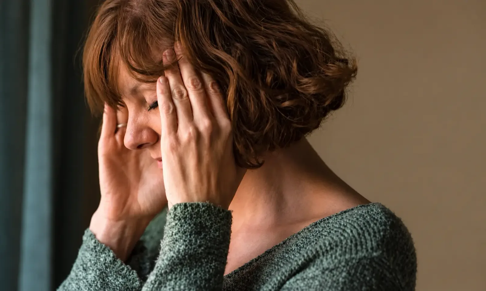 Woman holding her temples with her eyes closed