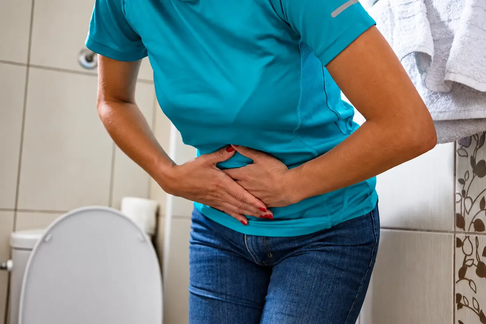 Woman holding her lower abdomen in a bathroom